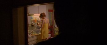 Movie still from “Enter the Void” (2009), directed by Gaspar Noé – A woman in a yellow dress in a kitchen; Medium shot, Over the shoulder angle