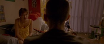 Movie still from “Enter the Void” (2009), directed by Gaspar Noé – A man sitting in front of a table with food on top of it; Medium shot, Over the shoulder angle