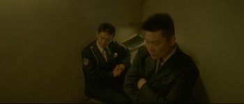 Movie still from “Enter the Void” (2009), directed by Gaspar Noé – Two men in suits are looking at their watches; Medium shot, High angle