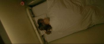 Movie still from “Enter the Void” (2009), directed by Gaspar Noé – A woman laying in bed with her head on a pillow; Medium shot, Overhead angle