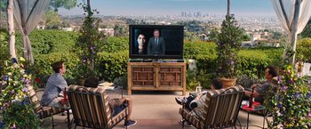 Two people sitting in front of a television on a television stand