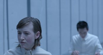 Movie still from “Equals” (2015), directed by Drake Doremus – Two people in white shirts are sitting in front of a wall; Close Up shot, Over the shoulder angle