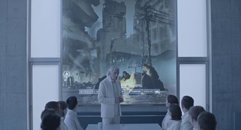 Movie still from “Equals” (2015), directed by Drake Doremus – An older man standing in front of a group of people; Wide shot, Over the shoulder angle