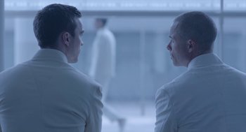 Movie still from “Equals” (2015), directed by Drake Doremus – Two men in white suits are looking at each other; Close Up shot, Over the shoulder angle