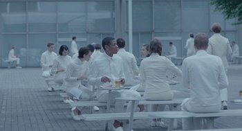 Movie still from “Equals” (2015), directed by Drake Doremus – A group of people sitting around a table eating food; Wide shot, High angle