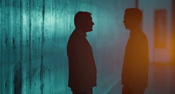 Movie still from “Equals” (2015), directed by Drake Doremus – Two men standing next to each other in front of a wall; Medium shot, Low angle