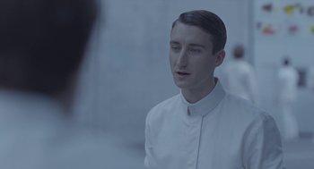 Movie still from “Equals” (2015), directed by Drake Doremus – A man wearing a white shirt is looking at the camera; Close Up shot, Over the shoulder angle