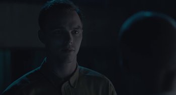 Movie still from “Equals” (2015), directed by Drake Doremus – A young man is looking at the camera in the dark; Close Up shot, Over the shoulder angle