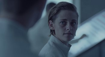 Movie still from “Equals” (2015), directed by Drake Doremus – A young man in a white shirt is looking at the camera; Close Up shot, Over the shoulder angle