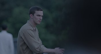 Movie still from “Equals” (2015), directed by Drake Doremus – A man in a brown shirt is looking at the camera; Medium shot, High angle