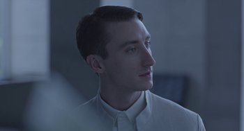 Movie still from “Equals” (2015), directed by Drake Doremus – A young man in a white shirt is looking to his left; Close Up shot, Low angle