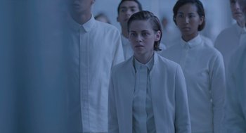 Movie still from “Equals” (2015), directed by Drake Doremus – A group of people in a room with a person in a white suit; Medium shot, Over the shoulder angle
