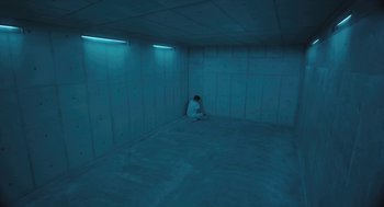 Movie still from “Equals” (2015), directed by Drake Doremus – A man sitting in a room with lights on the walls; Extreme Wide shot, High angle