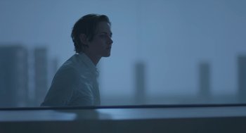 Movie still from “Equals” (2015), directed by Drake Doremus – A man in a white shirt is looking out of a window; Medium shot, Low angle