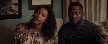 Movie still from “Game Night” (2018), directed by John Francis Daley – A woman and a man sitting next to each other on a couch; Close Up shot, Over the shoulder angle