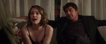 Movie still from “Game Night” (2018), directed by John Francis Daley – A man and a woman sitting next to each other on a couch; Medium shot, Over the shoulder angle