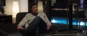 Movie still from “Game Night” (2018), directed by John Francis Daley – A man sitting in a chair in front of a television; Medium shot, High angle