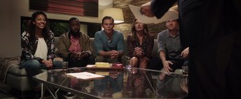 Movie still from “Game Night” (2018), directed by John Francis Daley – A group of people sitting around a glass table; Medium shot, High angle