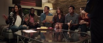Movie still from “Game Night” (2018), directed by John Francis Daley – A group of people sitting around a glass table; Medium shot, High angle