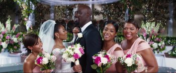 Movie still from “Girls Trip” (2017), directed by Malcolm D. Lee – Two women and a man standing next to each other holding bouquets; Medium shot, Over the shoulder angle