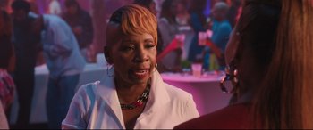 Movie still from “Girls Trip” (2017), directed by Malcolm D. Lee – An older woman with short blonde hair is smiling at a party; Close Up shot, Over the shoulder angle