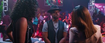 Movie still from “Girls Trip” (2017), directed by Malcolm D. Lee – A man wearing a hat and a vest in a room; Medium shot, Over the shoulder angle