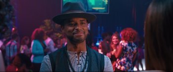 Movie still from “Girls Trip” (2017), directed by Malcolm D. Lee – A man wearing a hat and vest in front of a crowd of onlookers; Close Up shot, Over the shoulder angle