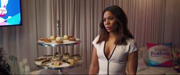 Movie still from “Girls Trip” (2017), directed by Malcolm D. Lee – A woman standing next to a table with a tray of cupcakes; Medium shot, Over the shoulder angle