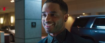 Movie still from “Girls Trip” (2017), directed by Malcolm D. Lee – A person wearing a suit and smiling; Close Up shot, Over the shoulder angle