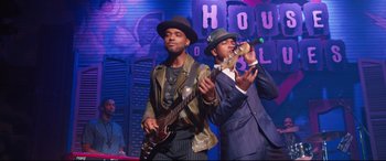 Movie still from “Girls Trip” (2017), directed by Malcolm D. Lee – A couple of men in suits and hats playing instruments on a stage; Medium shot, Low angle