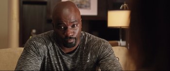 Movie still from “Girls Trip” (2017), directed by Malcolm D. Lee – A man sitting in front of a lamp in a room; Close Up shot, Over the shoulder angle