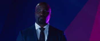 Movie still from “Girls Trip” (2017), directed by Malcolm D. Lee – A man wearing a suit and tie in a dark room; Close Up shot, Low angle