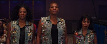 Movie still from “Girls Trip” (2017), directed by Malcolm D. Lee – A woman wearing a jean jacket with a lot of pins on it; Medium shot, Over the shoulder angle