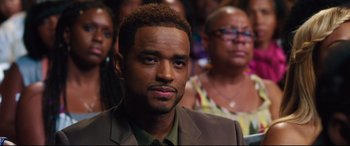 Movie still from “Girls Trip” (2017), directed by Malcolm D. Lee – A person sitting in a room with other people; Close Up shot, Over the shoulder angle