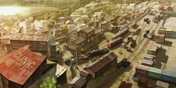 Movie still from “Evangelion: 3.0+1.01 Thrice Upon a Time” (2021), directed by Joe Fria – An aerial view of an old western town with trains; Extreme Wide shot, High angle