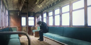 Movie still from “Evangelion: 3.0+1.01 Thrice Upon a Time” (2021), directed by Joe Fria – A man sitting on a bench in a train car; Wide shot, Low angle