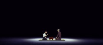 Movie still from “Evangelion: 3.0 You Can (Not) Redo” (2012), directed by Kiyotaka Suzuki – Two people sitting on the ground in front of an open laptop computer; Wide shot, High angle