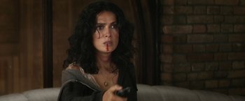 Movie still from “Everly” (2014), directed by Joe Lynch – A woman holding a tv remote in her hand; Close Up shot, Over the shoulder angle