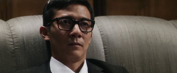 Movie still from “Everly” (2014), directed by Joe Lynch – A person wearing a suit and glasses; Close Up shot, High angle