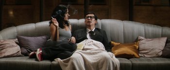 Movie still from “Everly” (2014), directed by Joe Lynch – A man and a woman sitting on a couch smoking a cigarette; Medium shot, Low angle