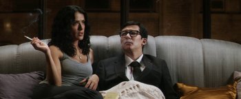 Movie still from “Everly” (2014), directed by Joe Lynch – A man and a woman sitting on a couch together; Medium shot, Low angle