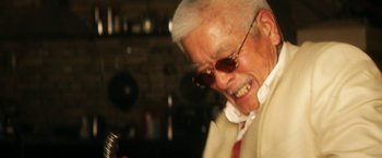 Movie still from “Everly” (2014), directed by Joe Lynch – An older man wearing a white shirt and red tie; Close Up shot, Low angle
