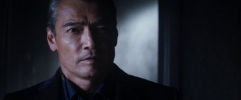 Movie still from “Everly” (2014), directed by Joe Lynch – A person wearing a suit and tie; Close Up shot, Over the shoulder angle