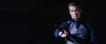 Movie still from “Everly” (2014), directed by Joe Lynch – A man holding a wooden stick in his hand; Medium shot, Low angle