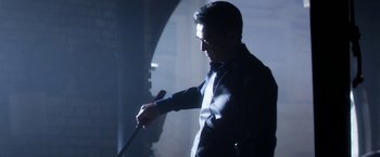 Movie still from “Everly” (2014), directed by Joe Lynch – A man holding a microphone in a dark room; Medium shot, Low angle