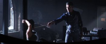Movie still from “Everly” (2014), directed by Joe Lynch – A man holding a wooden stick while standing next to a woman; Medium shot, Over the shoulder angle