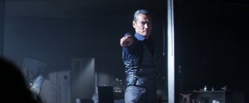 Movie still from “Everly” (2014), directed by Joe Lynch – A man pointing at the camera in a dark room; Medium shot, Low angle