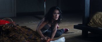 Movie still from “Everly” (2014), directed by Joe Lynch – A woman sitting on the ground in a dark room; Medium shot, Overhead angle