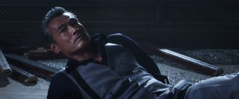 Movie still from “Everly” (2014), directed by Joe Lynch – A man in a suit and tie laying on the ground; Close Up shot, High angle