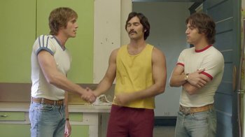 Movie still from “Everybody Wants Some!!” (2016), directed by Richard Linklater – A group of young men standing next to each other in a room; Medium shot, Over the shoulder angle